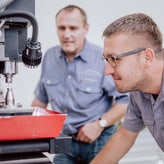 Deux mécaniciens tailleurs devant une grande machine dans l'atelier d'A. Lange & Söhne